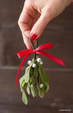 a hand is holding a small mist plant ornament with white berries and green leaves