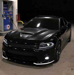 a black car parked in front of a gas pump