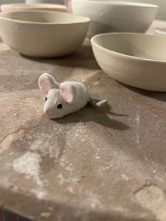 a toy mouse sitting on top of a table next to bowls