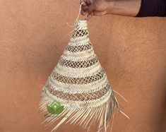 a hand holding a straw hat hanging from a wall