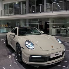 a white sports car parked in front of a large building with glass balconies