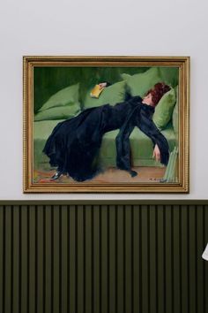 a painting hanging on the wall next to a green couch with a woman in black