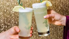 two people holding up glasses with drinks in them