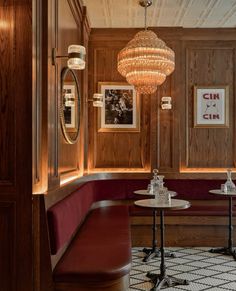 a restaurant with wood paneling and chandeliers hanging from the ceiling, along with red booths