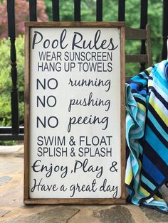 a sign that says pool rules on it next to a chair with a towel draped over it