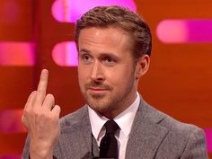 a man in a suit and tie making the peace sign with his hand while sitting down