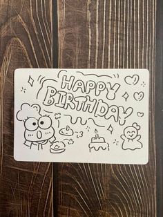 a happy birthday sticker is shown on a wooden surface with the words happy birthday written in black ink