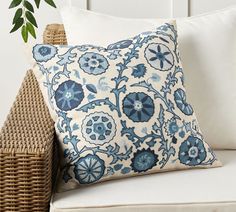 a blue and white pillow sitting on top of a couch next to a wicker basket