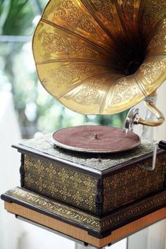 an old phonograph sitting on top of a wooden stand in front of a window