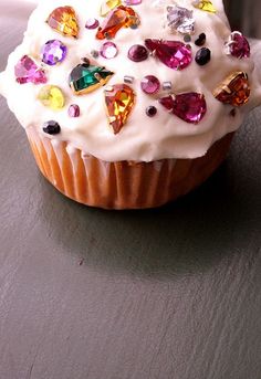 a cupcake with white frosting and colorful jewels