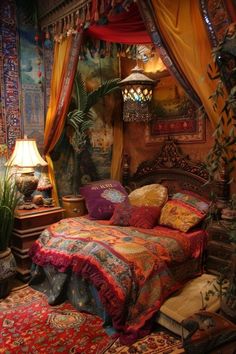 a bed covered in lots of colorful pillows next to a table with a lamp on it