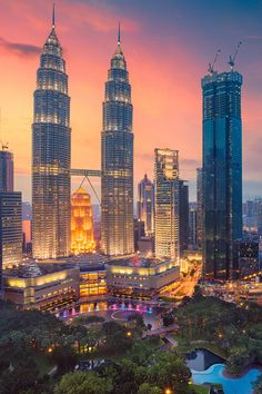 the city skyline is lit up at night with skyscrapers in the foreground and other tall buildings