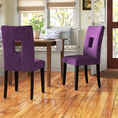 two purple chairs sitting next to each other on top of a hard wood floor in front of a window