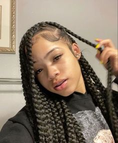 a woman with long braids in her hair is looking at the camera while holding a yellow marker