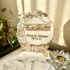 a white marble table topped with a glass vase filled with flowers and a personalized plaque