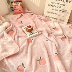 a pink blanket sitting on top of a bed next to a sign that says peach blossomery