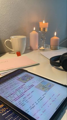 a tablet computer sitting on top of a desk next to a cup and headphones