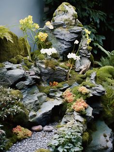 an arrangement of rocks and flowers is displayed in the middle of a garden area with moss