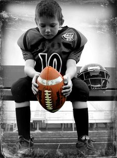 a young boy sitting on a bench holding a football