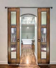 an open door leading to a bathroom with a tub and chandelier in the background