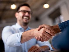 two men shaking hands while sitting at a table