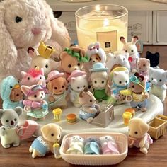 a bunch of stuffed animals sitting on top of a wooden table next to a candle