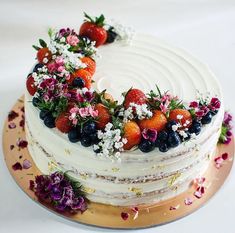 a cake decorated with fresh fruit and flowers on a gold platter for an anniversary celebration