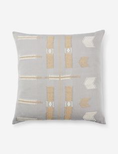 a gray and gold pillow with arrows on the front, along with a white background