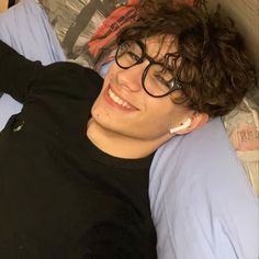 a young man laying in bed wearing glasses