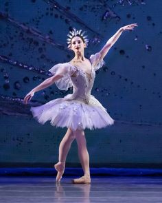 the ballerina is wearing a white tutu and holding her arms out with one hand