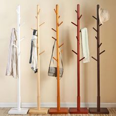 four coat racks with umbrellas and hats on them in front of a beige wall