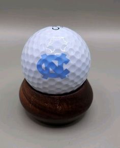 a white and blue golf ball sitting on top of a wooden stand with the university of north carolina logo