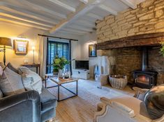 a living room filled with furniture and a fire place next to a stone wall covered in shutters