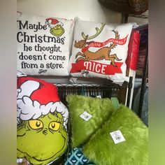 the grinch stuffed animal is on display in front of christmas pillows and other holiday decorations