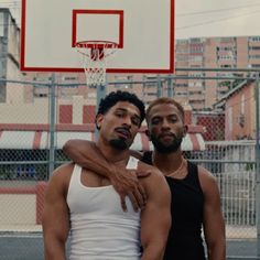 two men standing next to each other in front of a basketball hoop