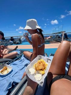 two women sitting on the deck of a boat eating food