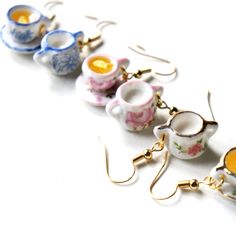 teacup earrings are lined up on a white surface