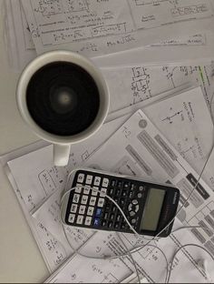 a calculator sitting on top of papers next to a cup of coffee