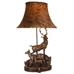 a lamp that is sitting on top of a table with a deer figurine underneath it