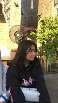 a woman sitting on top of a bench next to a man with a fan on his head