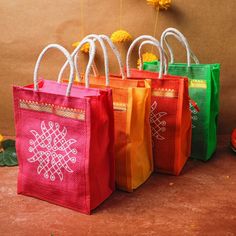 four bags with designs are lined up on the floor next to each other and some flowers