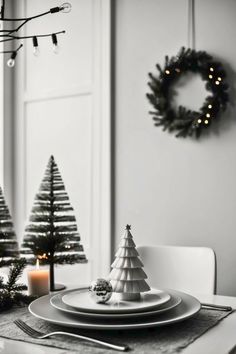 black and white christmas table setting with silverware, candlesticks and small trees