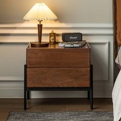 a bedside table with a lamp and phone on it