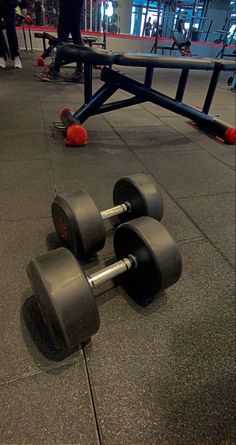 three dumbbells laying on the ground in an indoor gym