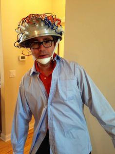 a man in a blue shirt wearing a silver helmet with wires on it's head