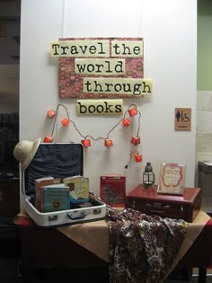 there is a suitcase and some books on the table in front of this sign that says travel the world through books