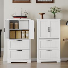 two white cupboards with drawers next to each other in front of a painting on the wall