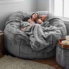 a woman laying in a bean bag chair with a blanket on it next to a coffee table