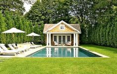 an outdoor pool with lounge chairs and umbrellas next to the swimming pool is surrounded by greenery