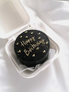 a black birthday cake in a foam container